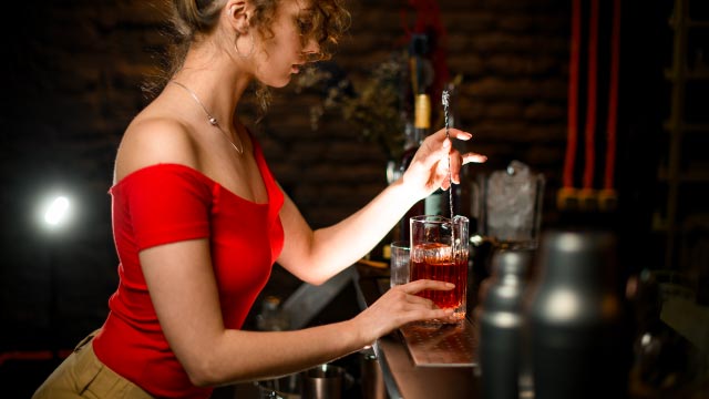 une femme sert un cocktail dans un bar